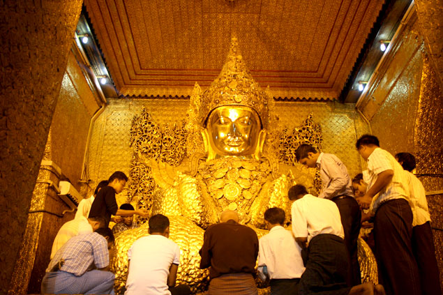 Fieles frotando pan de oro a la estatua de Buda