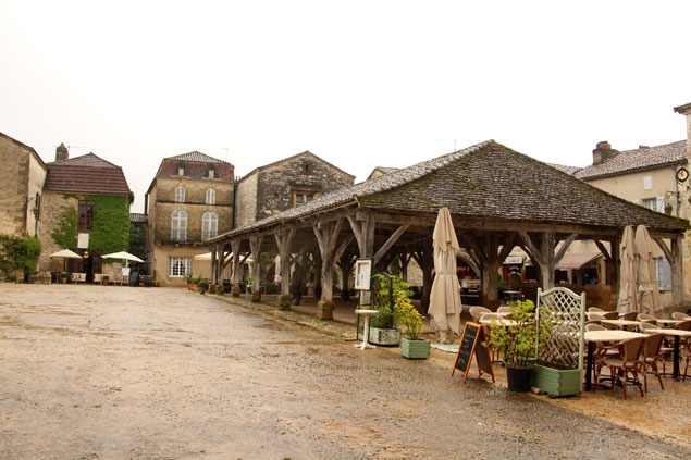 A la derecha , la estructura de madera del mercado de Monpazier